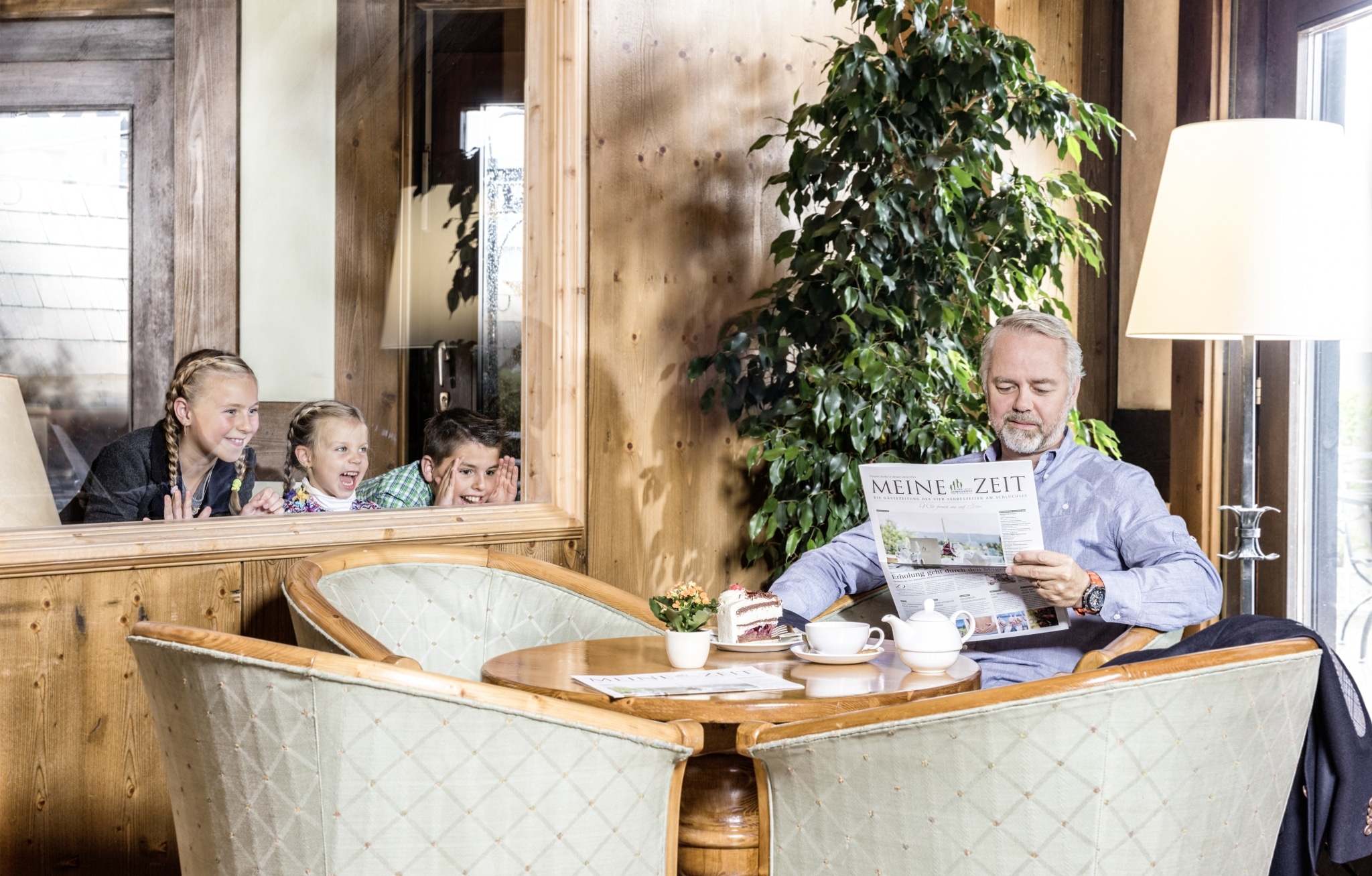 Kinder schauen Mann beim Lesen der Zeitung zu